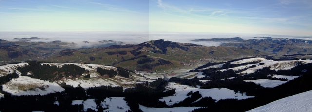 The Hundwiler hill as seen from the north launch on Kronberg. Look carefully and you will be able to spot paragliders. The landing paddock is visible in the center of the image.
