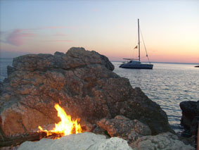 Romantisch, die Bucht von Lubinice nach den Flügen. Mit Lagerfeuer am Strand und dem Katamaran im Hintergrund